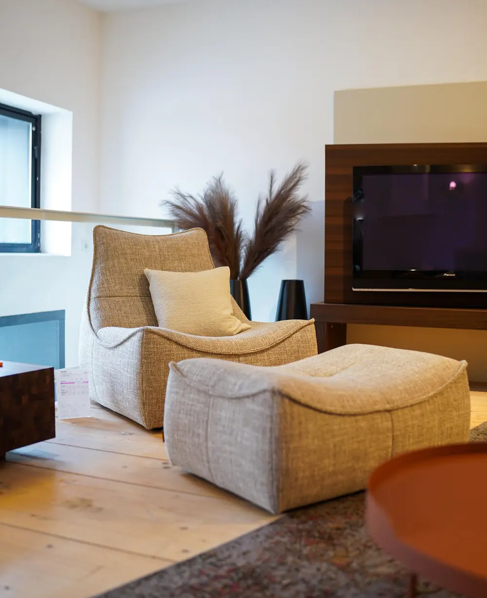 Gemütlicher Loungesessel mit Hocker in warmem Ambiente